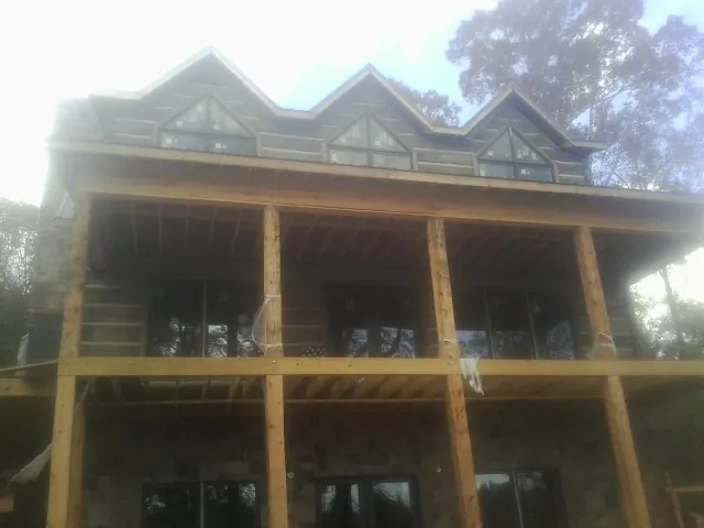 Dormers and porch framing on a large log home under construction — Roof Coating work by our crew in Black River Falls