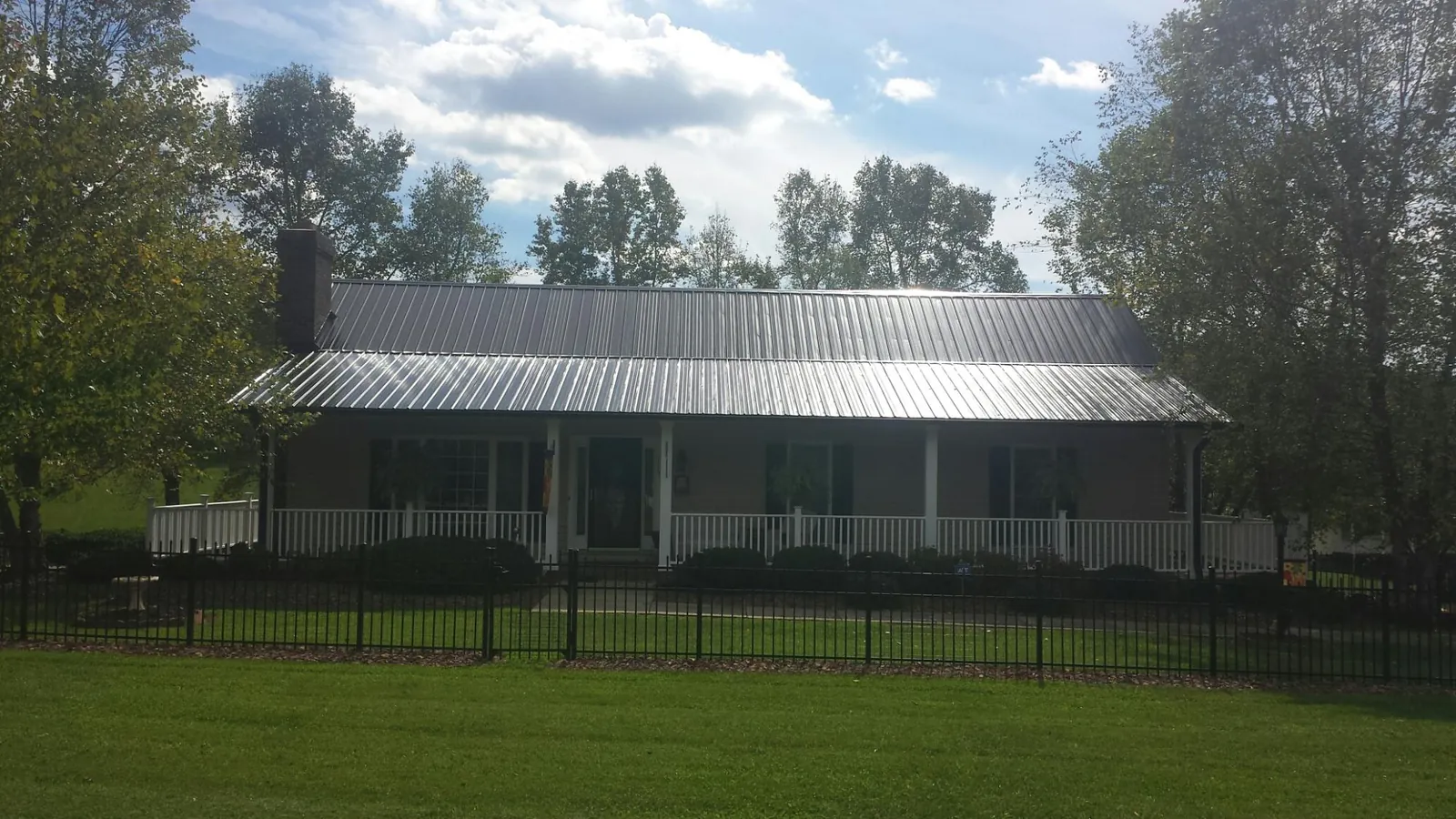 Gray metal roof on a brick ranch with a full width front porch — Gutter Guard Installation work by our crew in Black River Falls