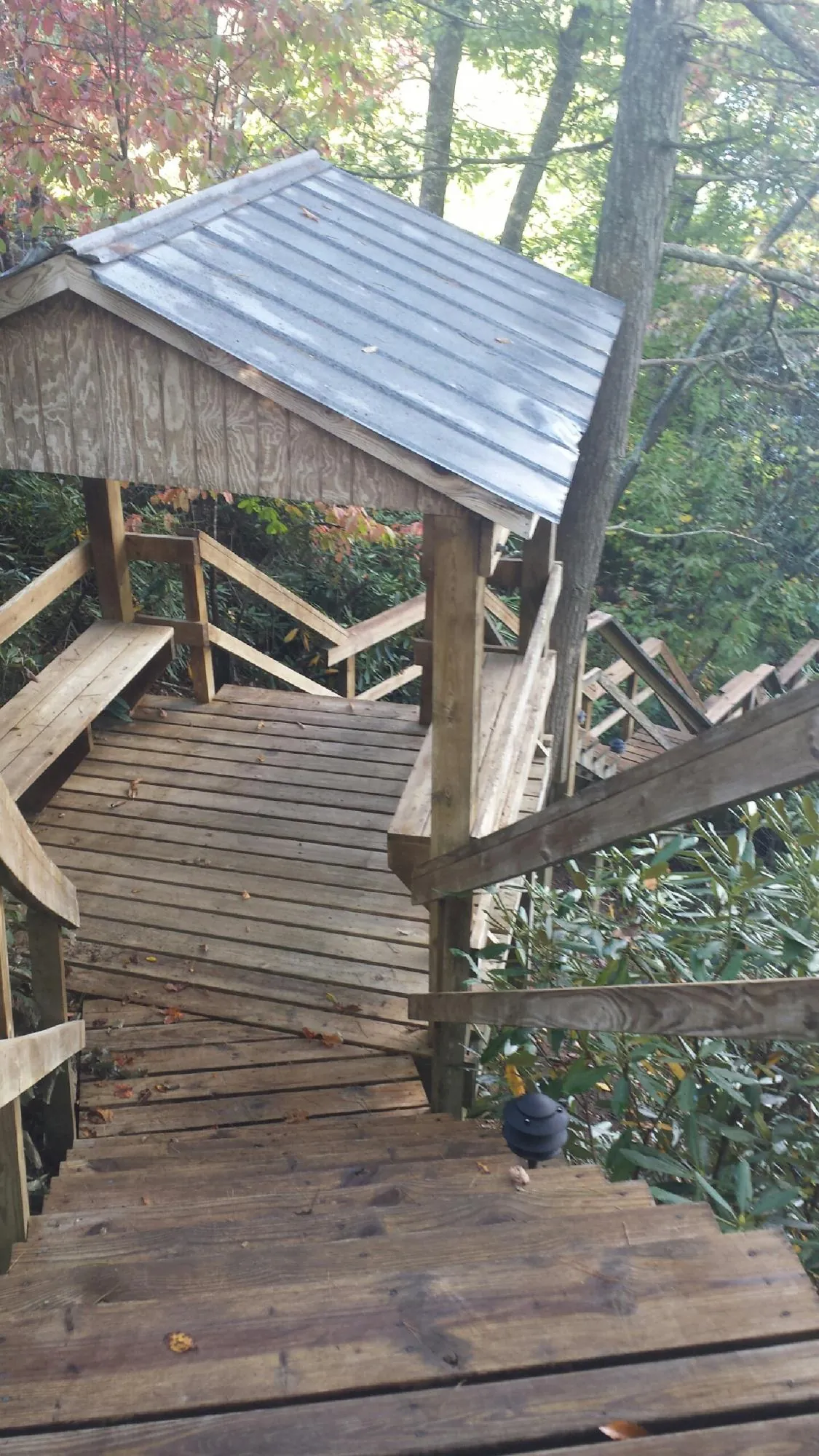 Metal roofed shelter over wooden steps on a wooded walkway — Skylight Repair & Installation work by our crew in Black River Falls