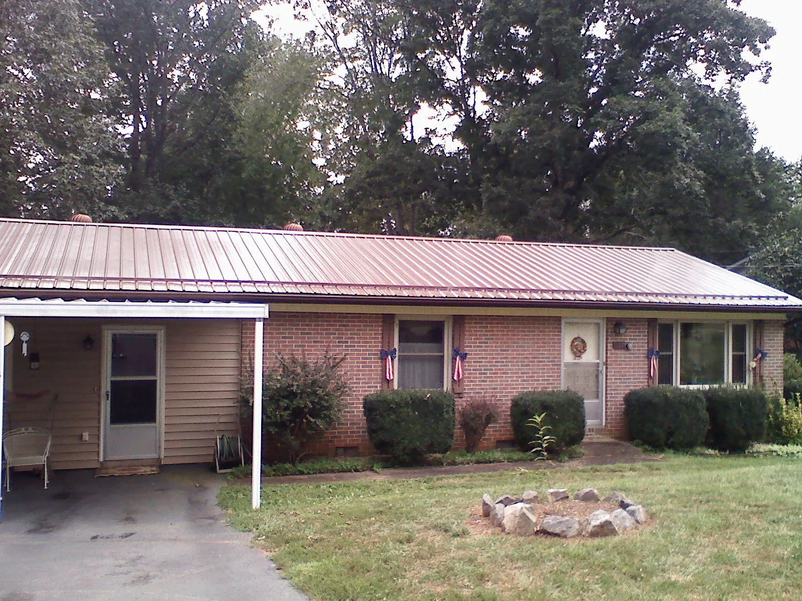 Bronze metal roof and carport on a brick ranch home — Roof Repair work by our crew in Black River Falls